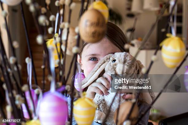 girl hiding behind easter bunny and twigs of pussy willows decorated with easter eggs - easter bunny with eggs stock pictures, royalty-free photos & images