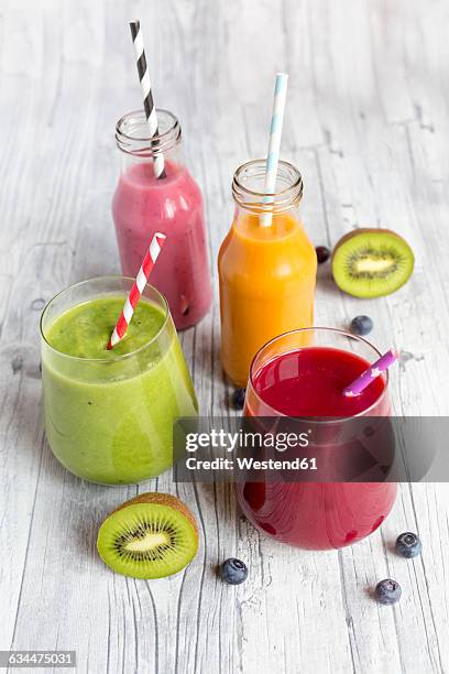 glasses of four different smoothies and fruits on wood - beetroot smoothie stock pictures, royalty-free photos & images