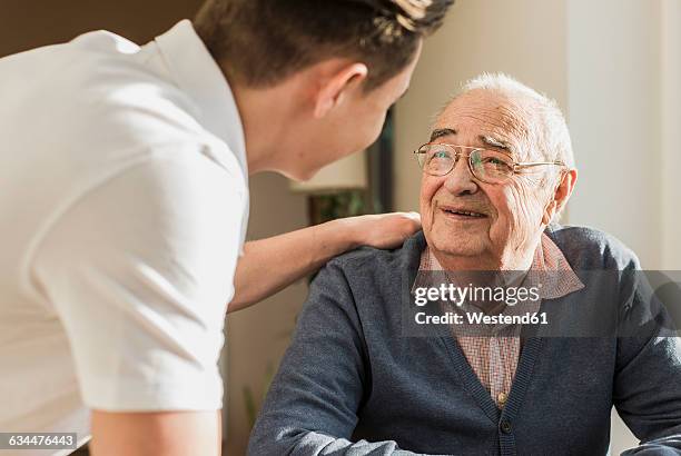 portrait of smiling senior man face to face with his geriatric nurse - pflege senioren stock-fotos und bilder