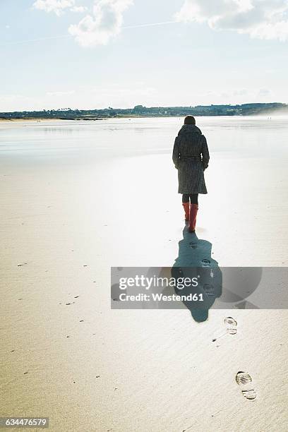 france, bretagne, finistere, crozon peninsula, woman walking on the beach - woman in coat from back stock pictures, royalty-free photos & images