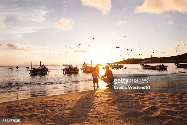 venezuela, isla margarita, juan griego, little boy and his grandfather at seafront by sunset - venezuela stock pictures, royalty-free photos & images