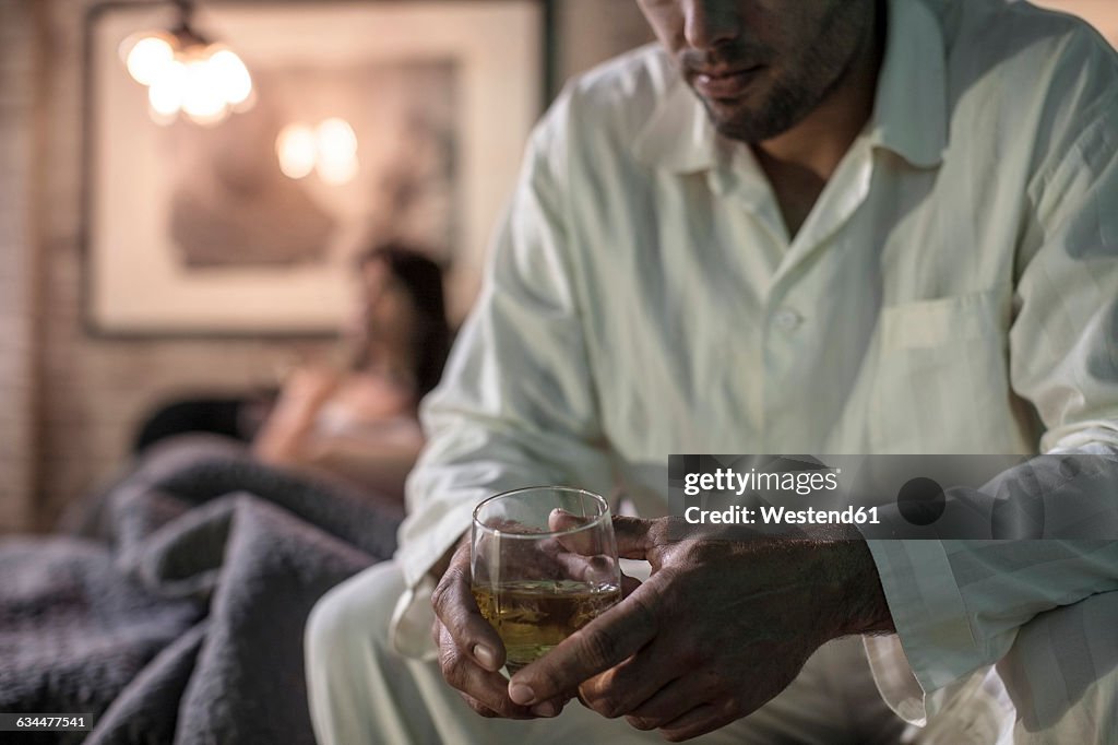 Man sitting on bed having a drink