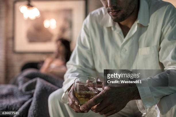 man sitting on bed having a drink - alcohol abuse stock pictures, royalty-free photos & images