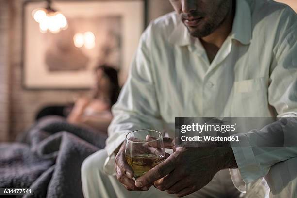 man sitting on bed having a drink - alcohol abuse 個照片及圖片檔