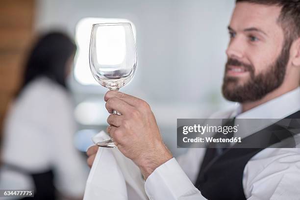 waiter polishing wine glasses in restaurant - abrillantar fotografías e imágenes de stock