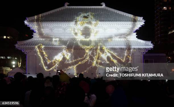 Visitors watch the projection mapping show at the snow statue of "the Central Golden Hall, Kofukuji temple in Nara" during the Sapporo Snow Festival...