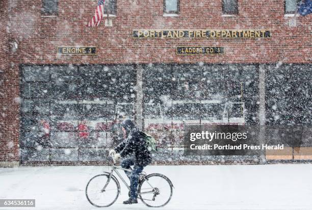 Bicyclist passes the Munjoy Hill fire station on Congress Street on Thursday morning as heavy snow falls throughout the region.