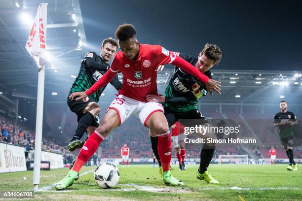 Jean-Philippe Gbamin of Mainz is challenged by Paul Verhaegh and Daniel Baier of Augsburg during the Bundesliga match between 1. FSV Mainz 05 and FC...