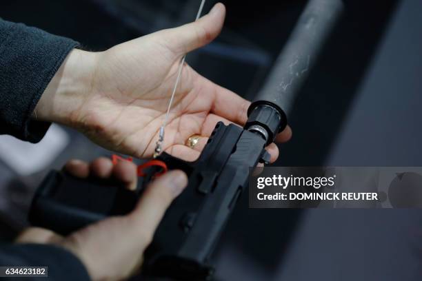 Visitor holds a pistol with a silencer at a gun display during a National Rifle Association outdoor sports trade show on February 10, 2017 in...