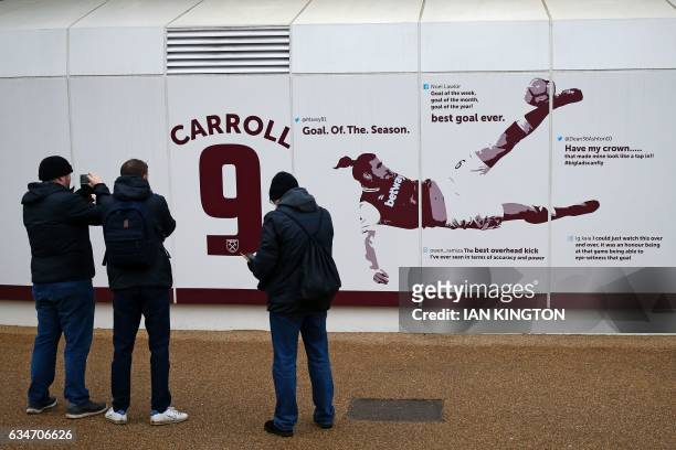 Supporters take pictures of the new mural of Andy Carroll's wonder goal against Crystal Palace on the outside of the stadium ahead of the English...