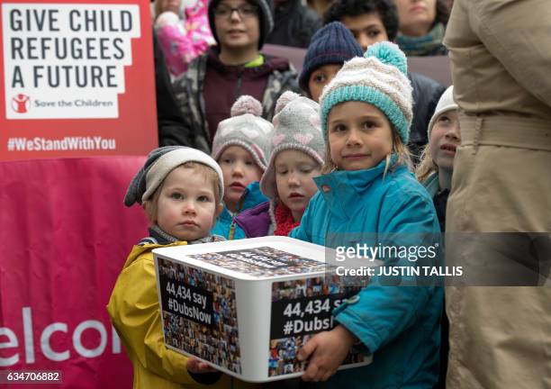 Children holds a box of signed petitions as people gather to hear speeches on Whitehall before Lord Alf Dubs handed in a petition to 10 Downing...