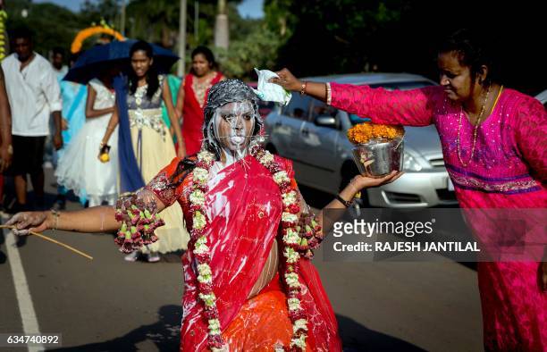 Hindu devotee with her body pierced with spikes and flowers gestures as milk is poured on her during the annual Hindu Thaipusam Kavady on February...