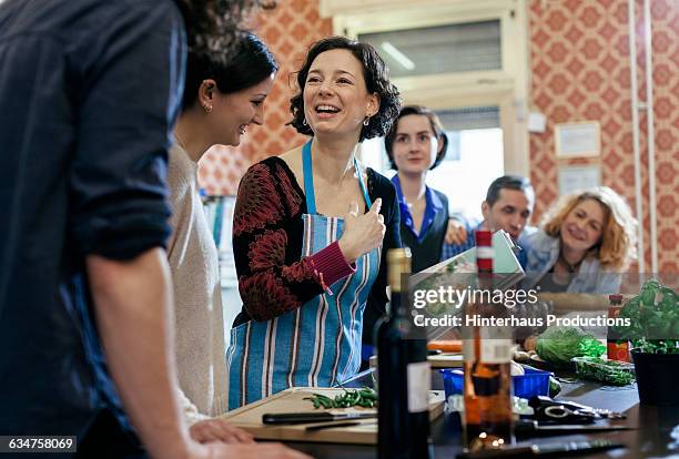 cooking instructor surrounded by curious students - livre de cuisine photos et images de collection