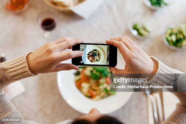 woman taking overhead photo of dinner - donna piatto foto e immagini stock