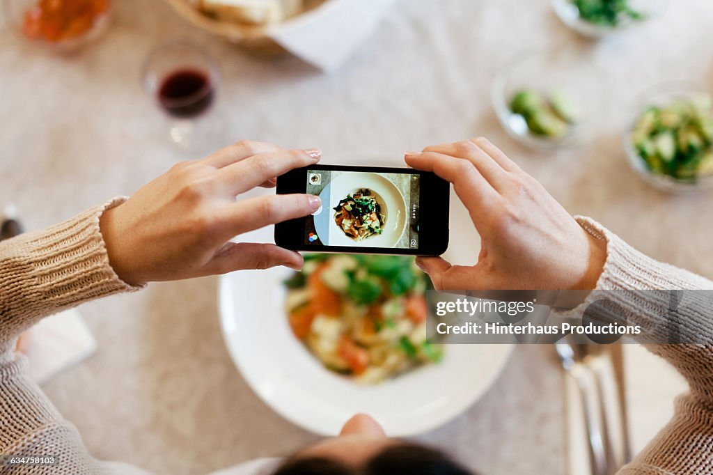 Woman taking overhead photo of dinner