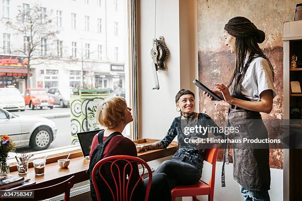 young women ordering something in a café - camarera fotografías e imágenes de stock