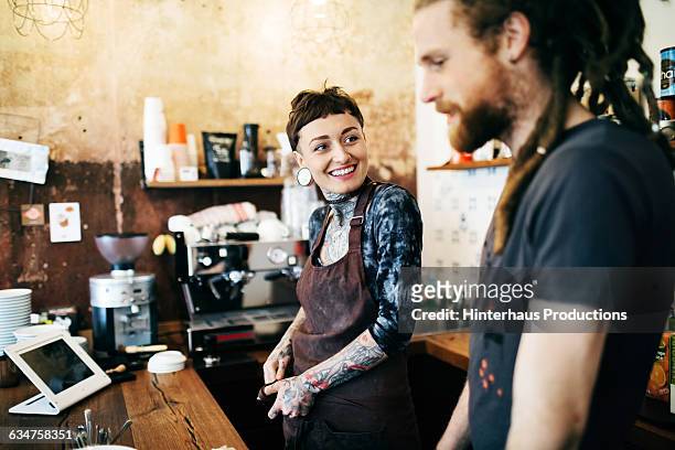 two young people behind the counter of a café - hipster coffee shop candid stock-fotos und bilder