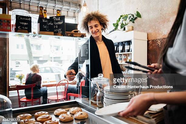 young man ordering some pastry in a café. - skåp med glasdörrar bildbanksfoton och bilder