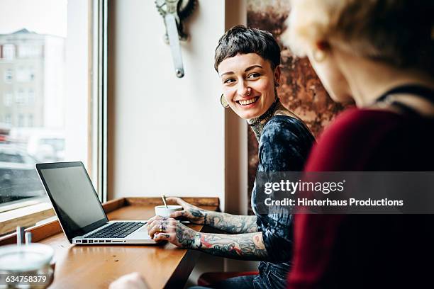 tattooed short-haired woman in a café - berlin cafe fotografías e imágenes de stock