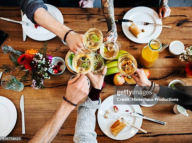 young people having a toast with a glass of wine. - friends toasting above table stock pictures, royalty-free photos & images