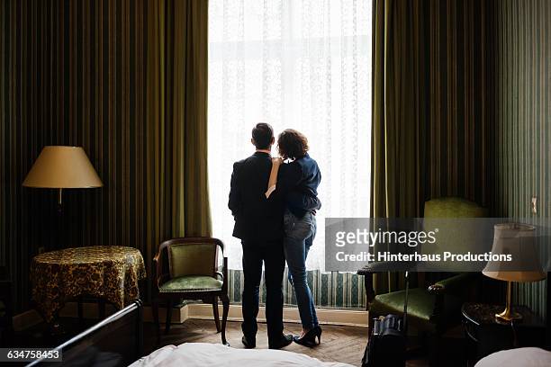 mature couple standing in front of a bright window - eleganz stock-fotos und bilder
