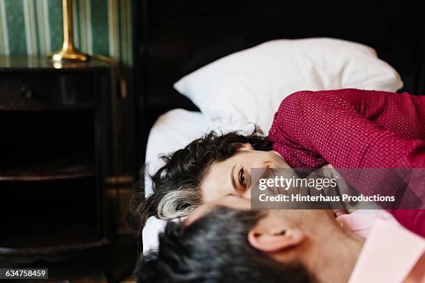 loving mature couple in a hotel bed. - frau mittellanges haar brünett stock-fotos und bilder