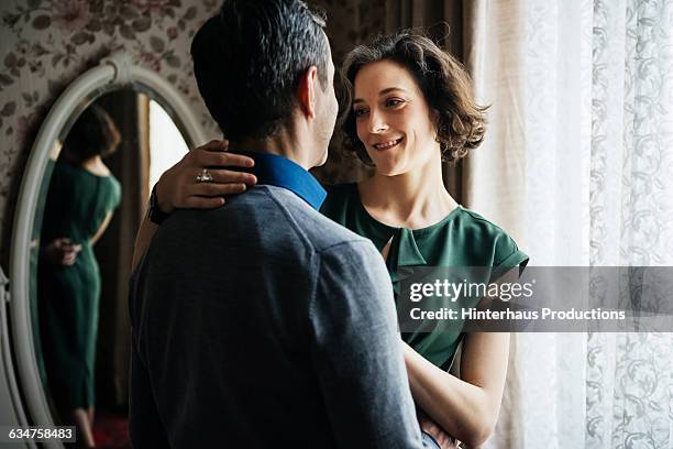 mature woman smiling at her partner in hotel room - dressing up imagens e fotografias de stock