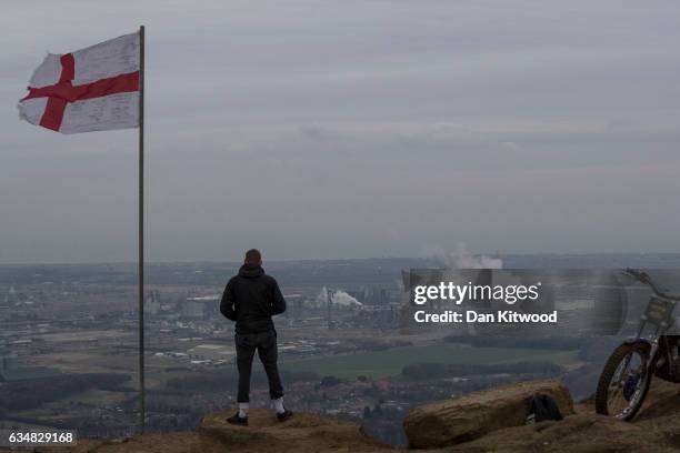 Young man stands on the top of Eston Nab in North Yorkshire, which looks down at the view over the industrial area of Teeside and Middlesbrough, on...