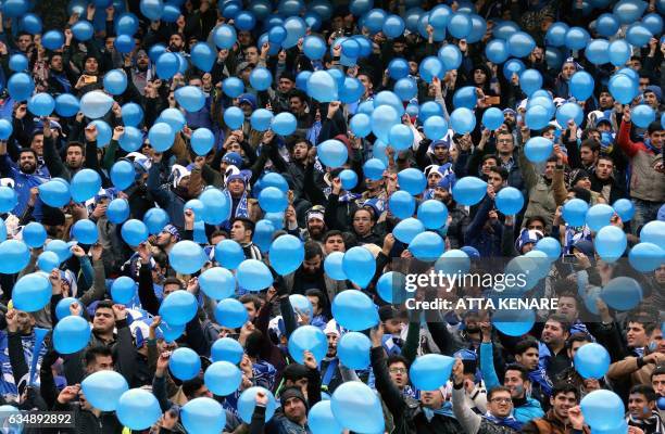 Esteghlal supporters hold balloons as they cheer on their team during the derby football match between Esteghlal and Persepolis at the Azadi stadium...