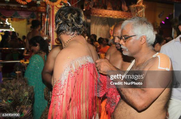 Tamil Hindu men remove hundreds of tiny hooks piercing the flesh of the back of a devotee who has completed special rituals as an act of penance...