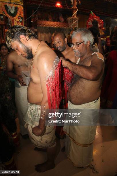 Tamil Hindu men remove hundreds of tiny hooks piercing the flesh of the back of a devotee who has completed special rituals as an act of penance...