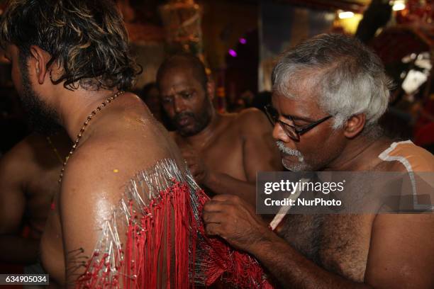 Tamil Hindu men remove hundreds of tiny hooks piercing the flesh of the back of a devotee who has completed special rituals as an act of penance...