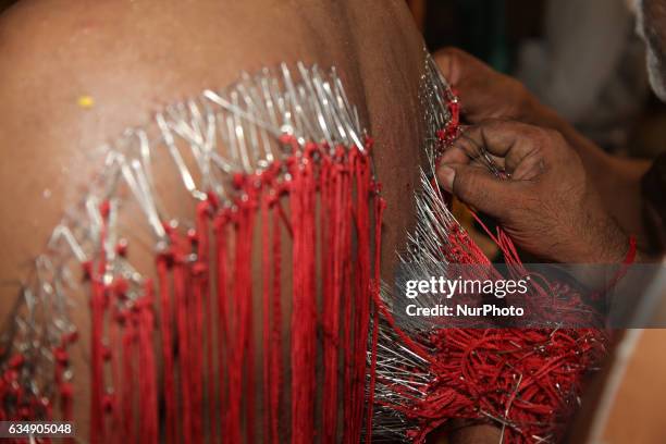 Tamil Hindu men remove hundreds of tiny hooks piercing the flesh of the back of a devotee who has completed special rituals as an act of penance...