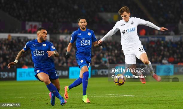 Tom Carroll of Swansea City takes on Danny Simpson and Riyad Mahrez of Leicester City during the Premier League match between Swansea City and...