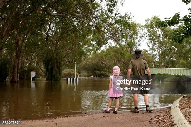 Man and his daughter look on as flood waters are seen in the Swan River on February 12, 2017 in the suburb of Herne Hill in Perth, Australia. Parts...