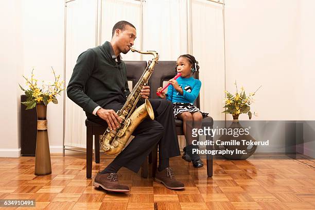 father and daughter at home playing music - woodwind instrument stock pictures, royalty-free photos & images