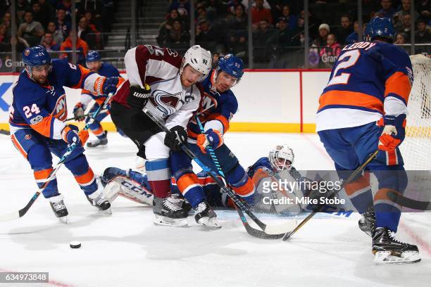 Casey Cizikas of the New York Islanders battles for the puck against Gabriel Landeskog of the Colorado Avalanche in front of Jean-Francois Berube at...