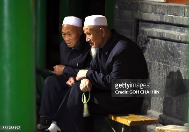 This picture taken on September 22, 2015 shows two Chinese Hui Muslims chatting after evening prayers at the Great Mosque of Tongxin, located some...