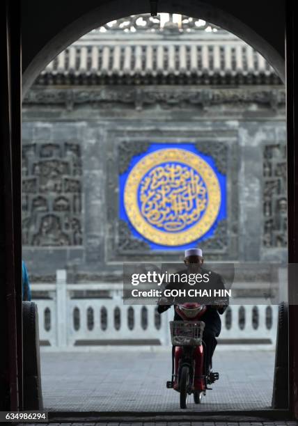 This picture taken on September 22, 2015 shows a Chinese Hui Muslim arriving for evening prayers on a motorbike at the Great Mosque of Tongxin,...