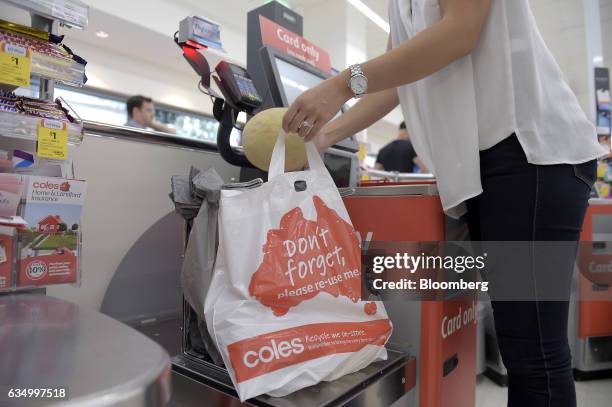 Customer places grocery items into a plastic bag at a self checkout counter in a Coles supermarket, operated by Wesfarmers Ltd., in the Richmond area...