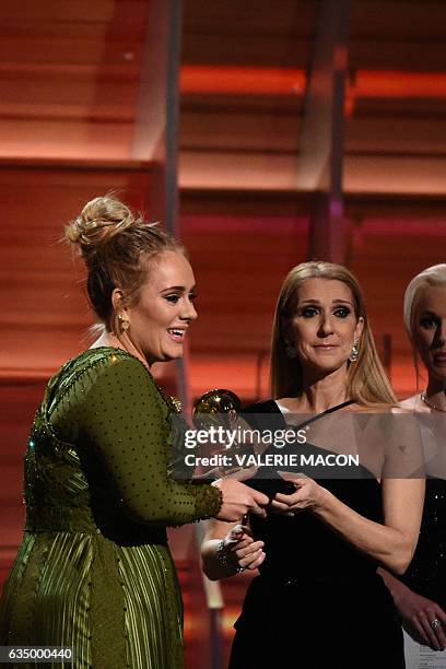 Adele receives the Grammyfor best song of the year from Celine Dion during the 59th Annual Grammy music Awards on February 12 in Los Angeles,...