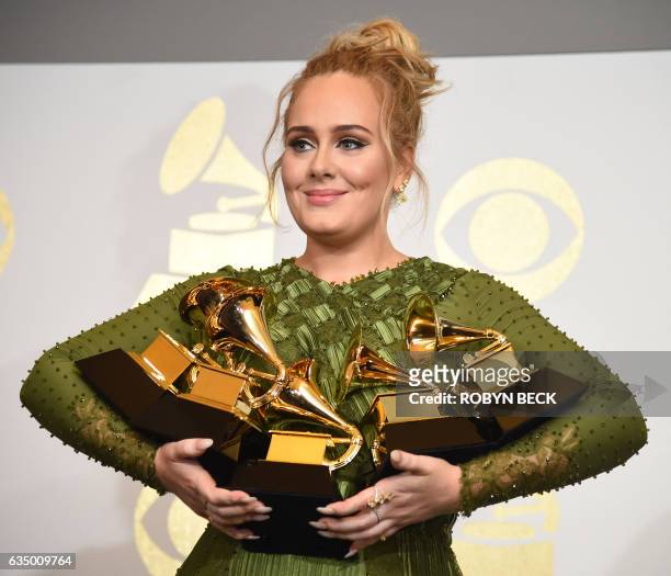 Adele poses in the press room with her trophies, including the top two Grammys of Album and Record of the Year for her blockbuster hit "Hello" and...