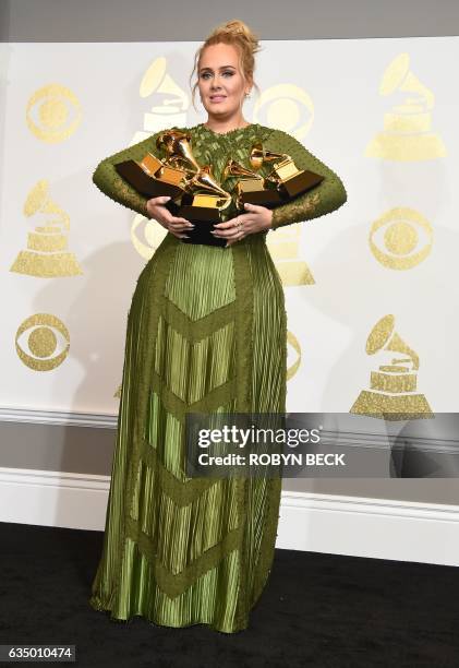 Adele poses in the press room with her trophies, including the top two Grammys of Album and Record of the Year for her blockbuster hit "Hello" and...