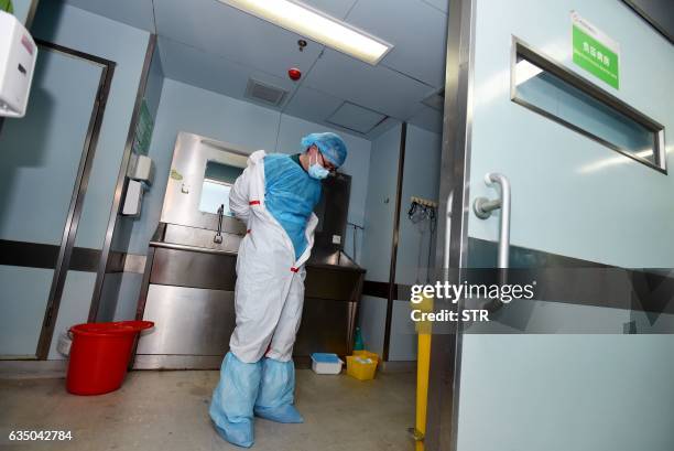 This photo taken on February 12, 2017 shows a member of staff taking off his decontamination suit after treating a H7N9 bird flu patient in a...