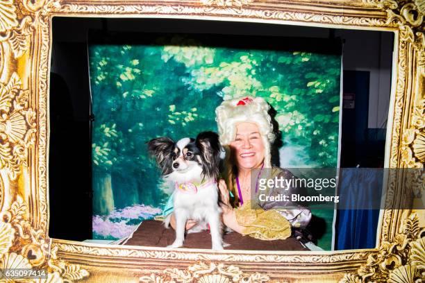 An owner dressed in costume sits for a photograph with her Papillion dog during the annual Meet the Breed event ahead of the 141st Westminster Kennel...