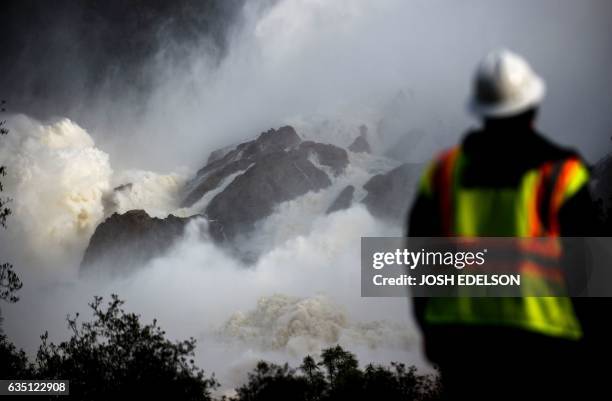 Water utility worker looks towards discharging water as it is released down a spillway as an emergency measure at the Oroville Dam in Oroville,...