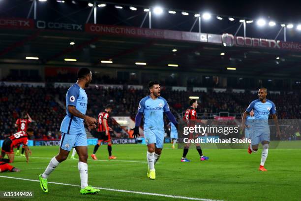 Sergio Aguero of Manchester City celebrates with Raheem Sterling and Fernandinho after sliding in next to Tyrone Mings of Bournemouth to score his...