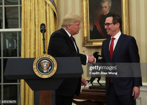 Former investment banker for Goldman Sachs Steven Mnuchin shakes hands with President Donald Trump during a swearing-in ceremony in the Oval Office...