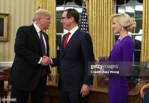 Former investment banker for Goldman Sachs Steven Mnuchin shakes hands with President Donald Trump as fiancee Louise Linton looks on during a...