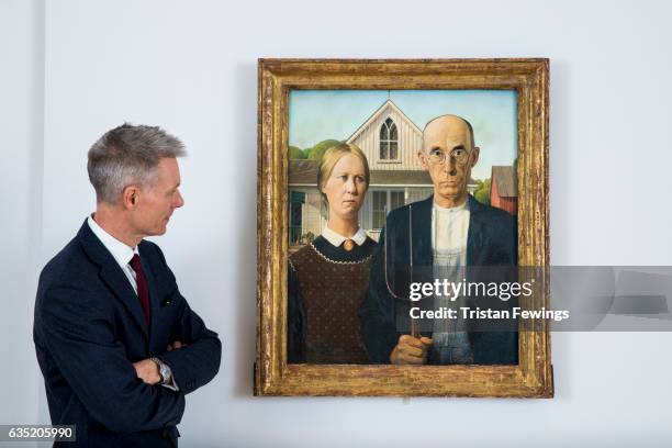 Tim Marlow, Artistic Director at the Royal Academy of Arts stands next to the iconic painting American Gothic, 1930 by Grant Wood, as it is installed...